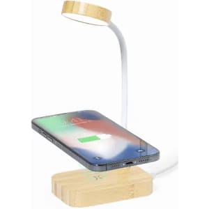 A wireless charging lamp with a bamboo base and a flexible arm, featuring a smartphone charging on top.