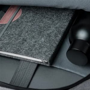 A drink bottle in black, alongside a grey felt notebook, inside a bag with grey lining. The image features a branding logo.