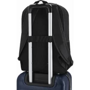 A black backpack featuring adjustable straps and a trolley handle, resting on a blue suitcase.
