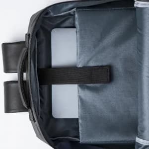A black and grey backpack interior, featuring compartments and a strap for securing a device.