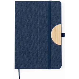 A notebook with a blue fabric cover and a wooden accent. It features an elastic band and a ribbon bookmark.