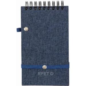 A notebook with a denim-patterned cover, spiral binding, and an elastic strap. It has a logo on the front.