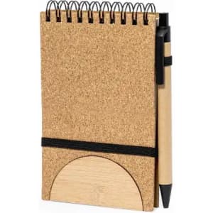 A cork notebook with a black spiral binding and a matching pen attached, featuring a wooden circle design at the base.