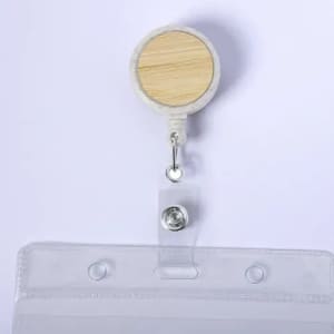 A badge reel with a wooden circular top and a clear plastic strap for securing identification or cards.