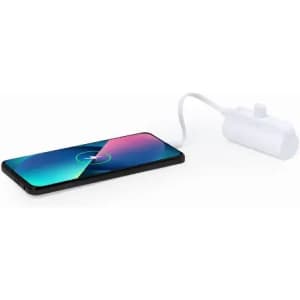 A wireless charging pad in white, connected to a smartphone displaying a charging indicator on its screen.