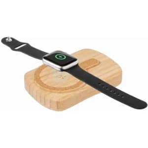 A watch resting on a wooden charging pad, featuring a silver frame and a black strap. The pad has a circular design.