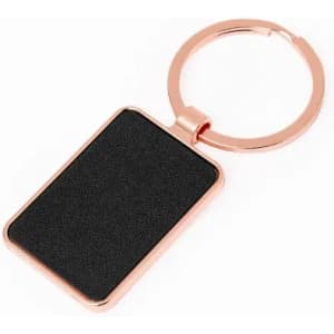 A keyring with a rectangular black surface and a rose gold metal frame. It includes a circular attachment loop.