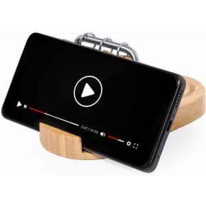 A smartphone on a wooden stand displaying a video player interface with a play button.