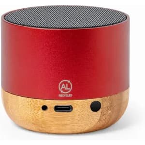 A small red speaker with a bamboo base and a mesh top, featuring a logo and ports on the side.
