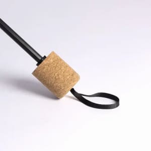 A drink bottle with a cork base, black straw, and a black strap. The bottle features a minimalist design.