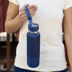 A drink bottle in navy blue with a silicone grip and a built-in strap, held by a person.