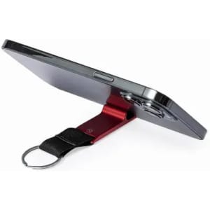 A phone with a red stand attached, featuring a black strap and keyring. The device is positioned horizontally.