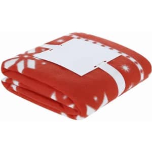 A red fleece blanket with a white snowflake pattern, neatly folded and secured with a white band.