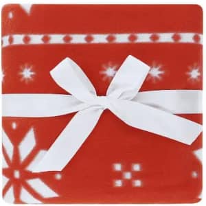 A red fleece blanket with a white ribbon tied around it, featuring a snowflake pattern.