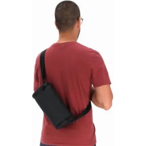 A black drink bottle with a strap, held by a person wearing a red shirt. The person is facing away from the camera.