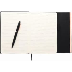 A notebook with a black cover, cream-lined pages, and a black pen resting on the open pages.