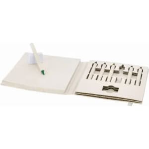 A notebook with a pen resting on it, featuring cut-out sections for crayons or coloured pencils. Light-coloured pages.