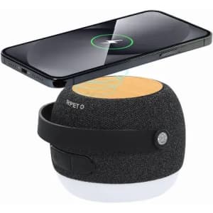 A wireless charger with a black fabric exterior and a wooden top, positioned near a smartphone for charging.