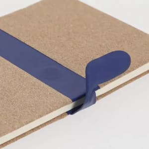 A notebook with a cardboard cover and a blue elastic band securing it closed.