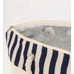 A bag with a navy and cream striped exterior, featuring a silver interior and a zip closure.