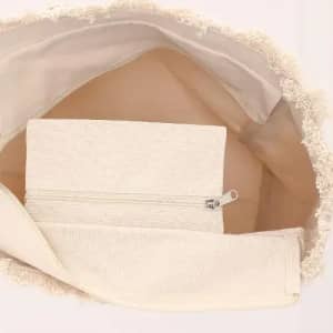 A tote bag in cream colour with an inner pocket and a zippered pouch, featuring a textured edge.