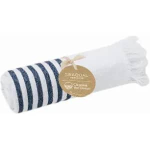 A rolled towel with navy stripes and a white section, featuring a tag and frayed edges.