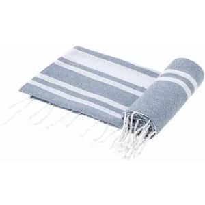 A rolled grey and white striped towel with decorative fringe edges.