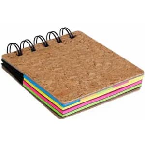 A cork-covered notebook with spiral binding, featuring brightly coloured pages in pink, green, yellow, and blue.
