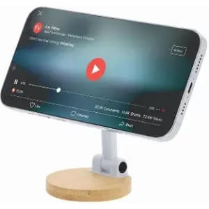 A phone stand with a wooden base holds a smartphone displaying a video playback screen. The stand is white.