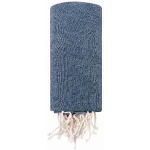 A blue woven towel with fringed edges, neatly rolled up. It features a textured pattern throughout.