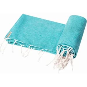 A rolled-up turquoise beach towel with white fringes, featuring a small logo tag.