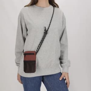 A crossbody bag featuring a textured black and maroon design, worn over a grey sweatshirt.