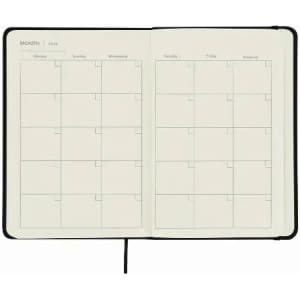 A planner notebook with a black cover, featuring blank monthly calendar pages in a grid layout.