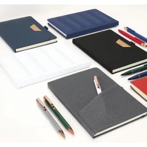 A collection of notebooks in various colours, including navy, black, white, grey, and red, alongside several pens.