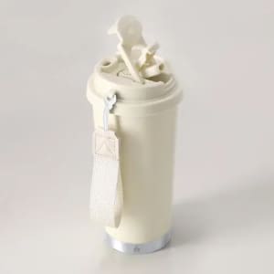 A drink bottle in cream colour with a textured grip and a metallic base, featuring a lid and strap attachment.