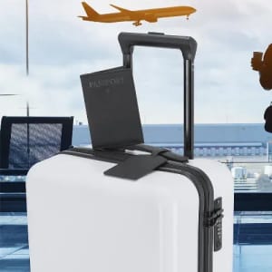 A white suitcase with a black handle, featuring a passport and luggage tag, set against an airport backdrop.