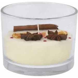 A glass candle featuring a white wax base, topped with cinnamon, star anise, and dried fruit decorations.