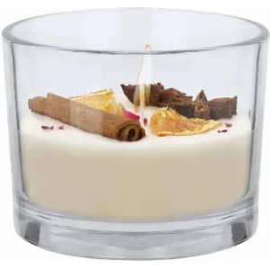 A candle in a clear glass holder featuring a creamy white wax, adorned with cinnamon sticks and dried petals.