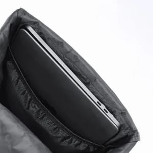 A black laptop partially secured in a grey fabric sleeve with a zippered pocket. The sleeve has a soft interior lining.