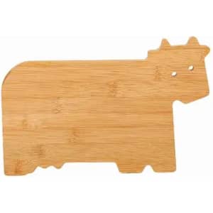 A bamboo chopping board shaped like a cow, featuring two holes for eyes. Wood tones are visible.