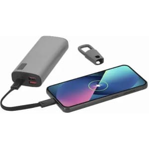 A portable power bank in grey connected to a smartphone with a charging cable, featuring a keychain attachment.