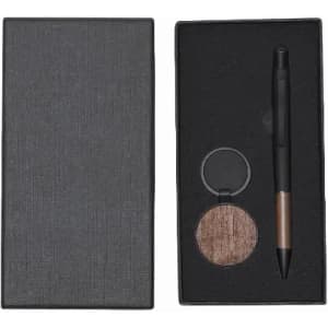A gift box containing a pen and a circular compact in a dark grey casing. The compact features a brown shade.