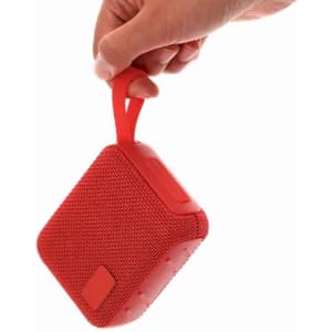 A red Groxen Speaker being held by a hand, featuring a textured surface and a convenient carrying strap.