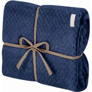 A folded navy blue blanket tied with a tan ribbon, showcasing a textured pattern. It has a simple branding label.
