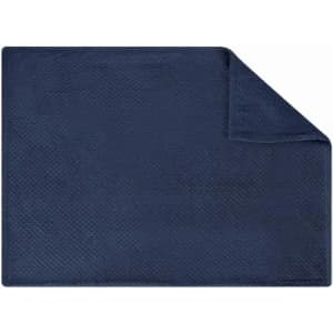 A navy blue bath mat with a textured surface and a folded corner. It has a simple, solid design.