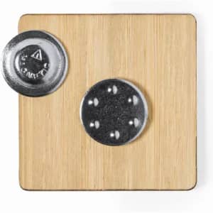 A square bamboo coaster with a metal disc attached, featuring a silver finish and circular indentations.
