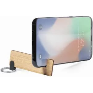 A phone stand made of wood, featuring a keyring attachment, supporting a smartphone with a colourful screen.