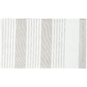 A bath mat featuring a striped design in shades of white and light grey. It has a textured surface and a logo.