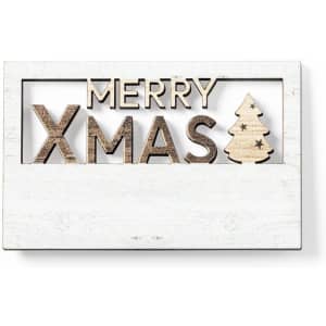 A wooden decorative sign featuring the words "MERRY XMAS" and a small Christmas tree design, set against a white background.
