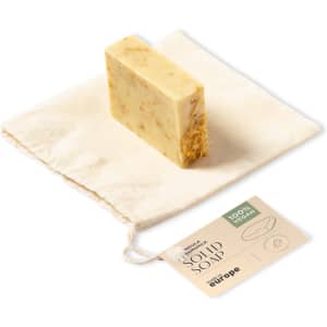 A solid soap bar in a natural shade, presented on a small cloth pouch with a tag.
